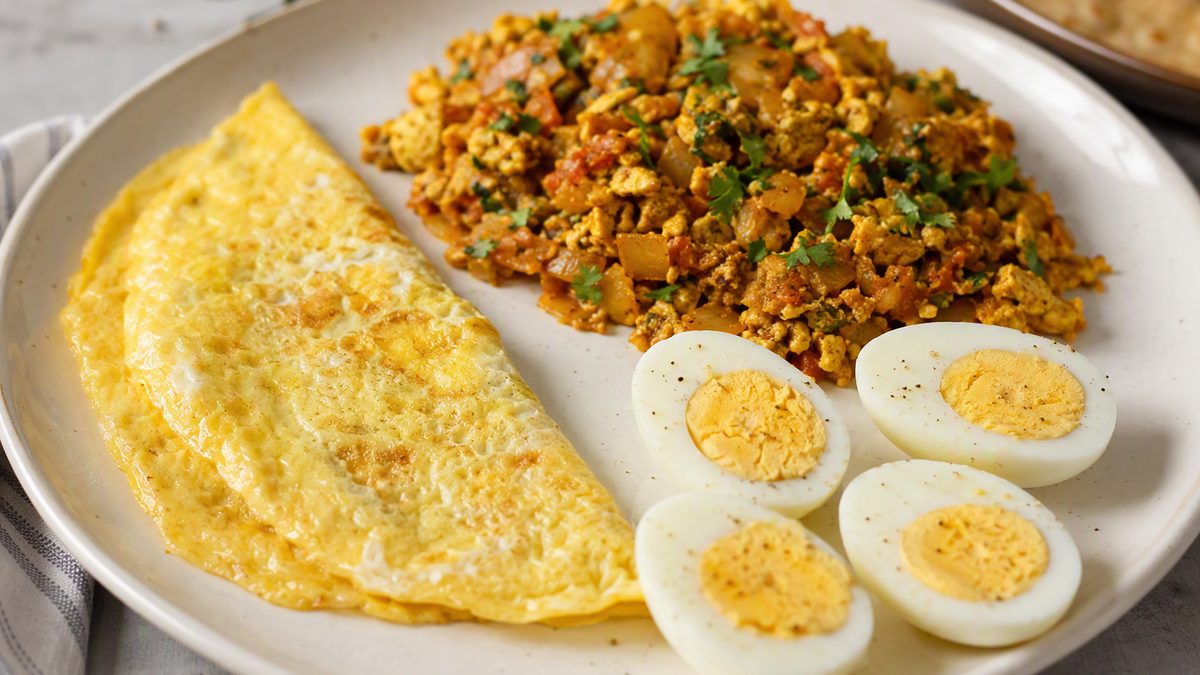 Boiled eggs halved, an omelette and egg bhurji on one plate