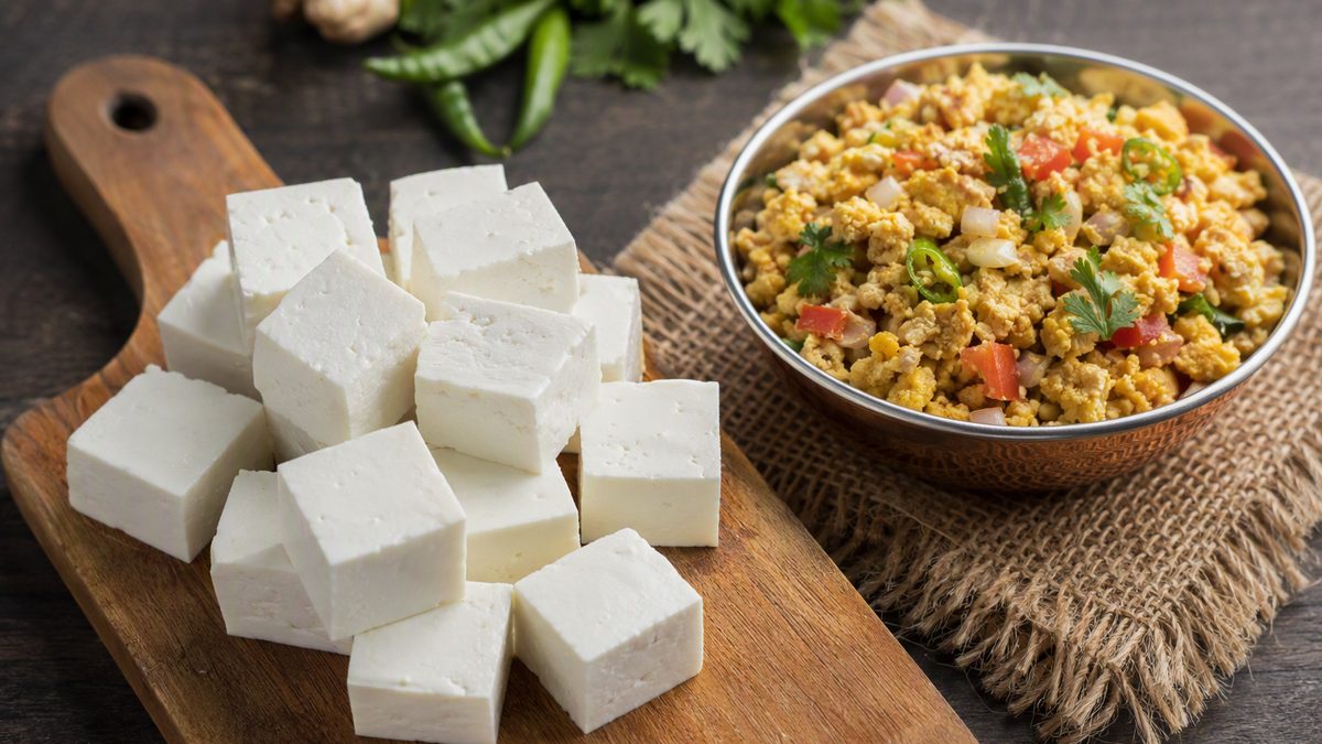 Cubes of fresh paneer on a board, small katori of paneer bhurji